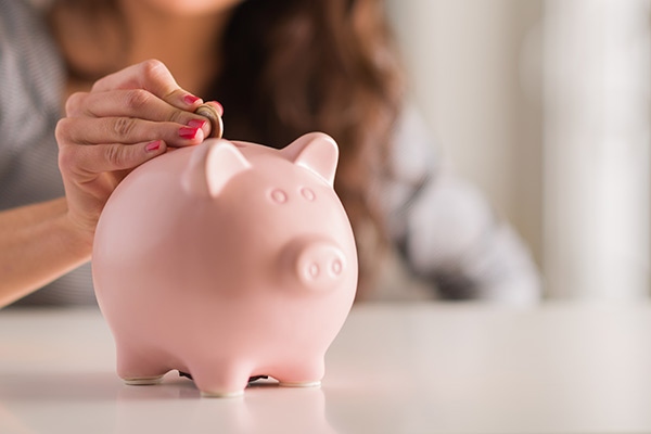 Girl adding a coin to a piggy bank