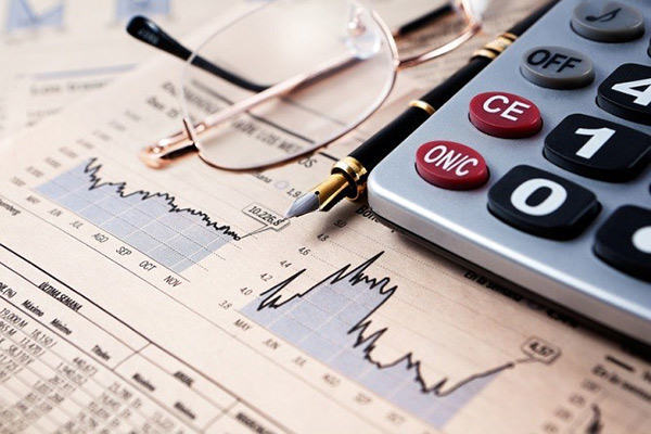 Glasses, pen, calculator and a stack of papers with graphs and numbers