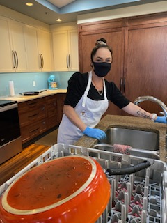 alt="Amanda Woolward washing dishes in the kitchen at the Ronald McDonald House in Red Deer"