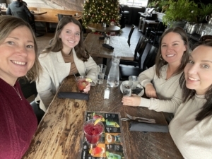 alt="4 TPTM team members seated at a table in a restaurant"